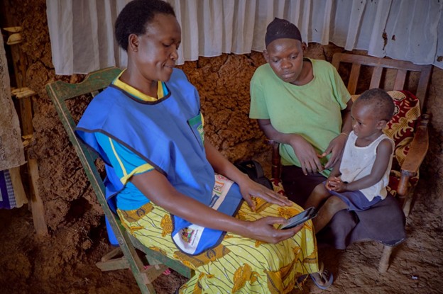 woman uses mobile to enter data while speaking with mother and child